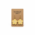 A pair of handmade yellow crocheted flower drop earrings with small white pearl-like centers and gold hooks, displayed on a brown kraft card that reads 'handmade with' against a white background.