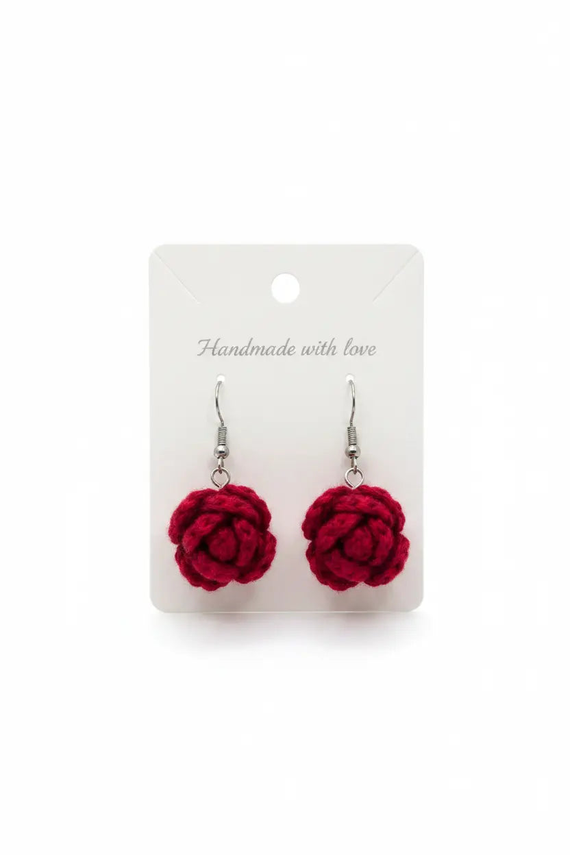 A pair of handmade red crochet rose drop earrings on silver fishhook wires, displayed on a white backing card that reads 'Handmade with love'.