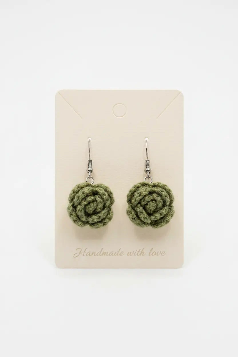 A pair of handmade olive green crocheted flower dangle earrings on a beige display card that reads 'Handmade with love' against a white background.