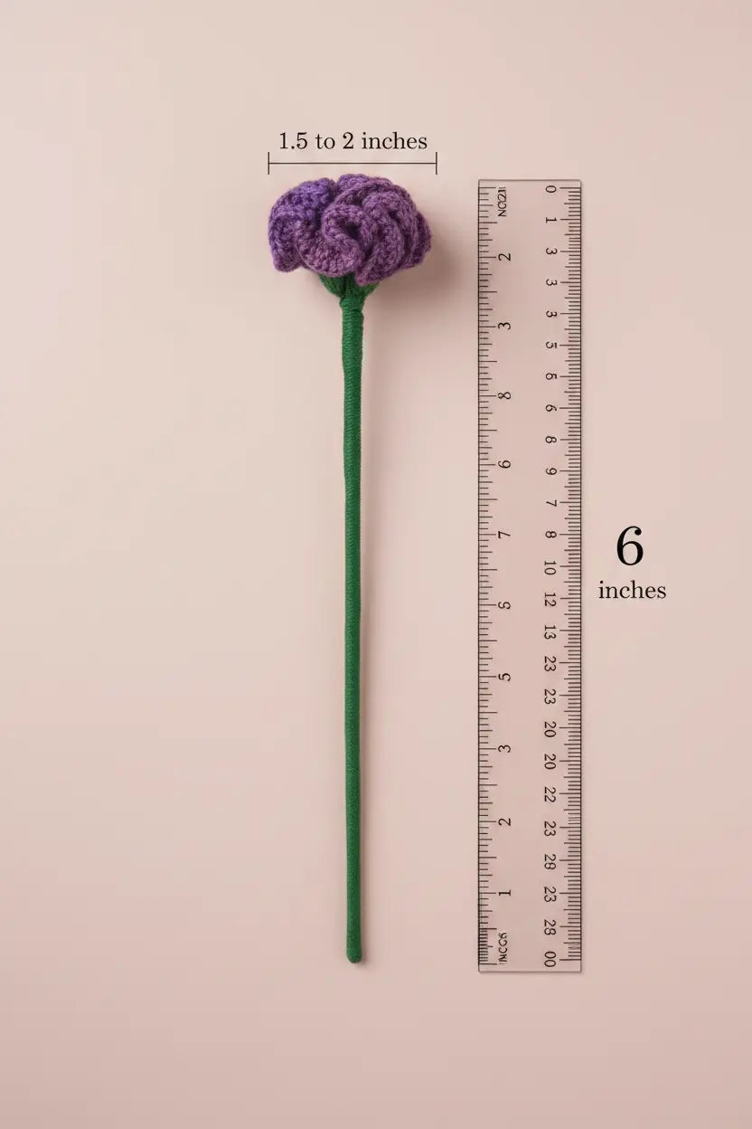 A single purple crocheted flower stem with a green stem is shown on a pale pink background, alongside a ruler indicating the stem is 6 inches long and the flower head is 1.5 to 2 inches wide.