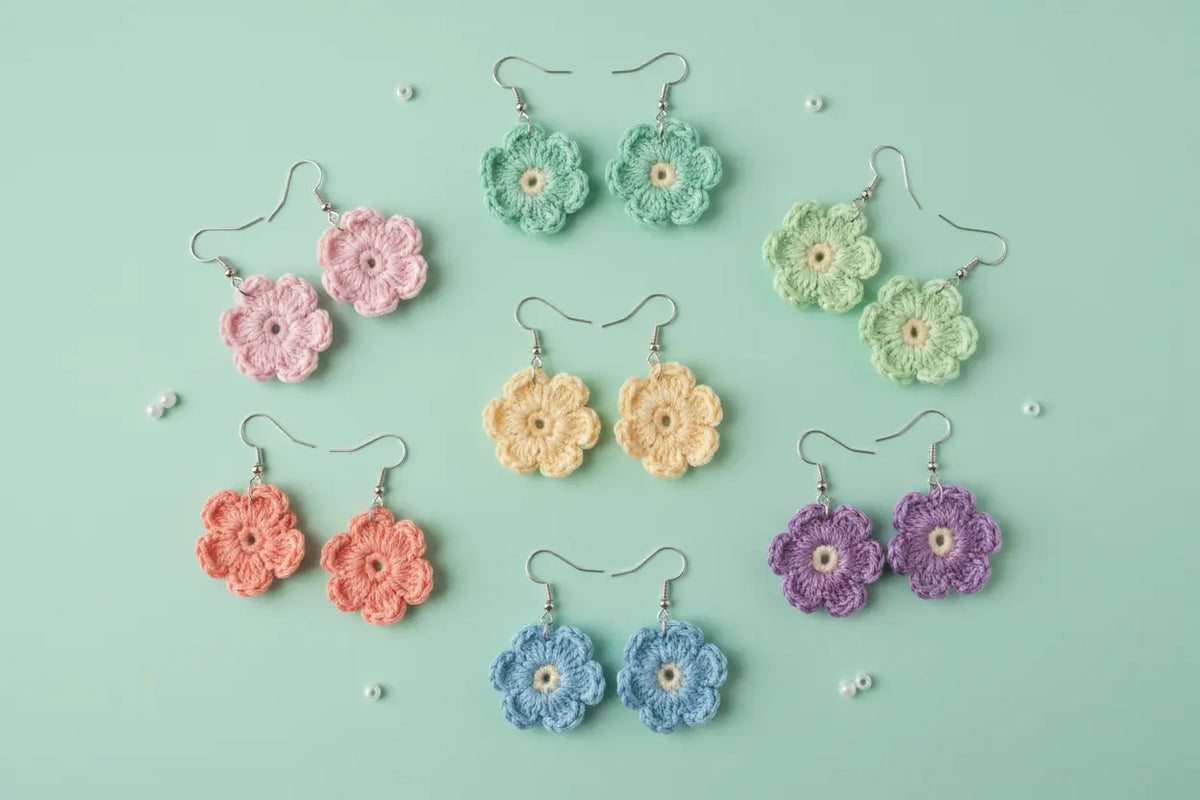 Six pairs of handmade crocheted flower dangle earrings in pastel pink, mint green, light green, coral orange, light blue, and lavender purple, arranged on a mint green background with small decorative pearls.